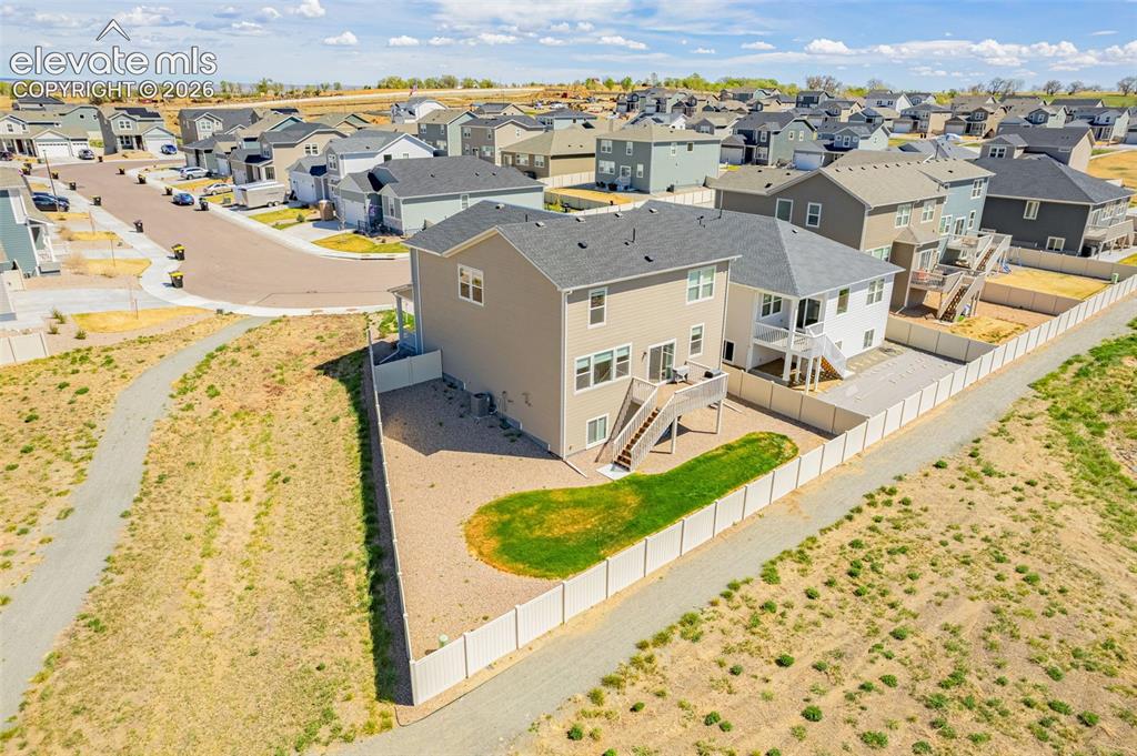 Image 46 of 50: Two-story residence with a neutral exterior, featuring a private fenced yar