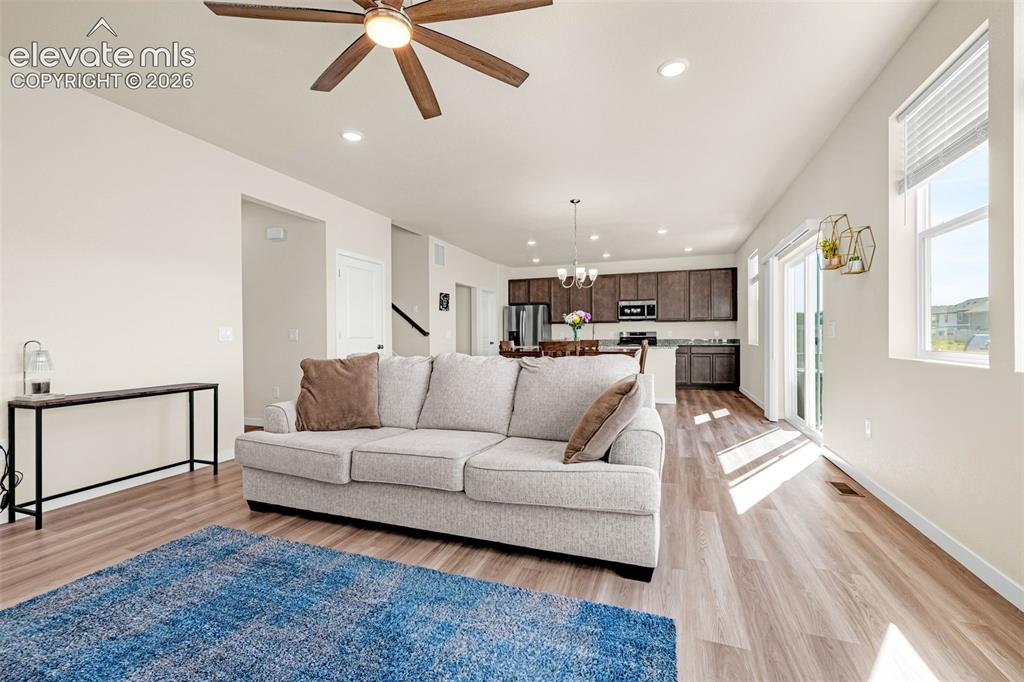 Image 5 of 50: Open-concept living space featuring wood-finish flooring, recessed lighting