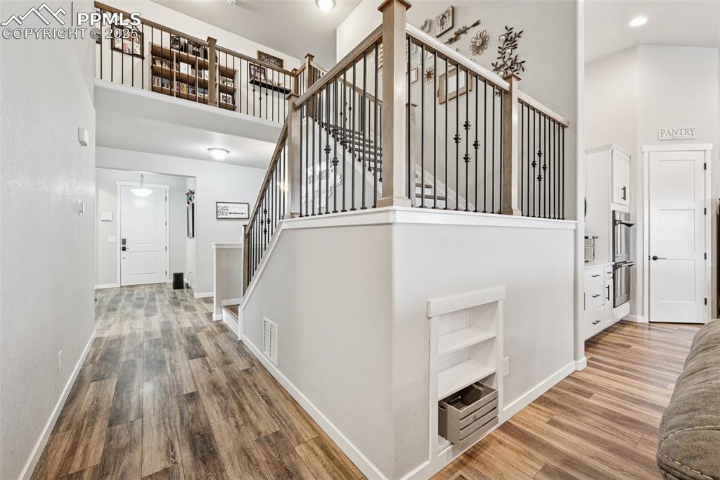 Image 15 of 40: Stairs featuring a towering ceiling and wood finished floors
