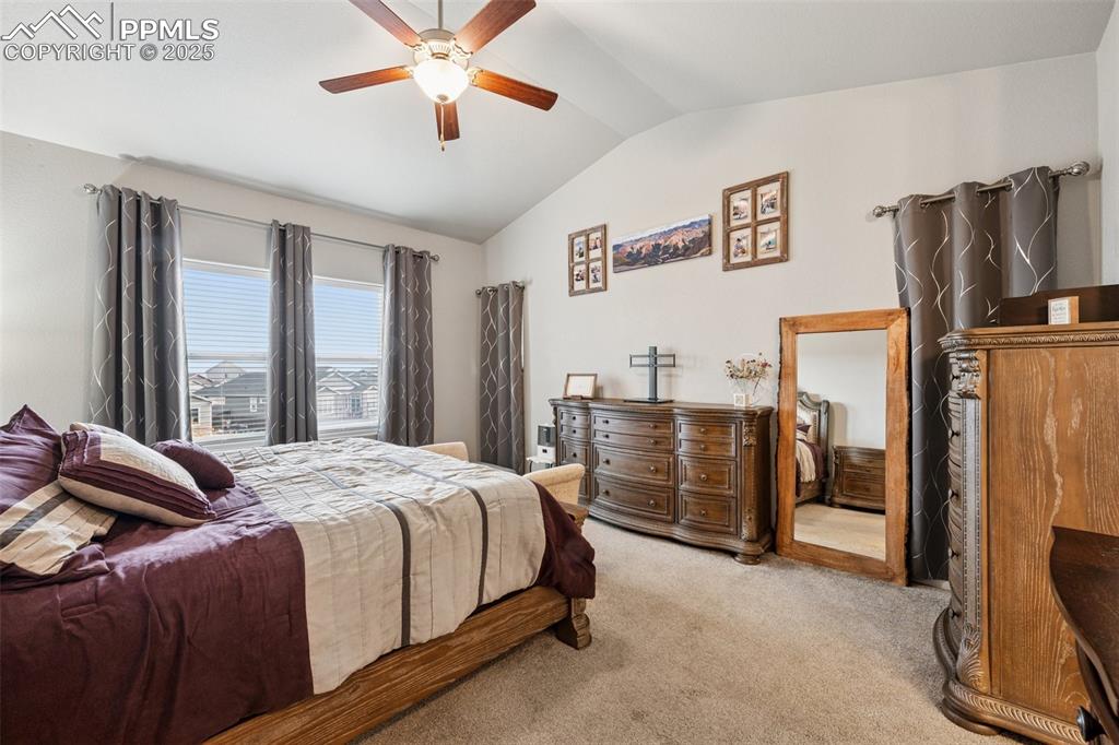 Image 17 of 40: Bedroom featuring vaulted ceiling, carpet floors, and a ceiling fan