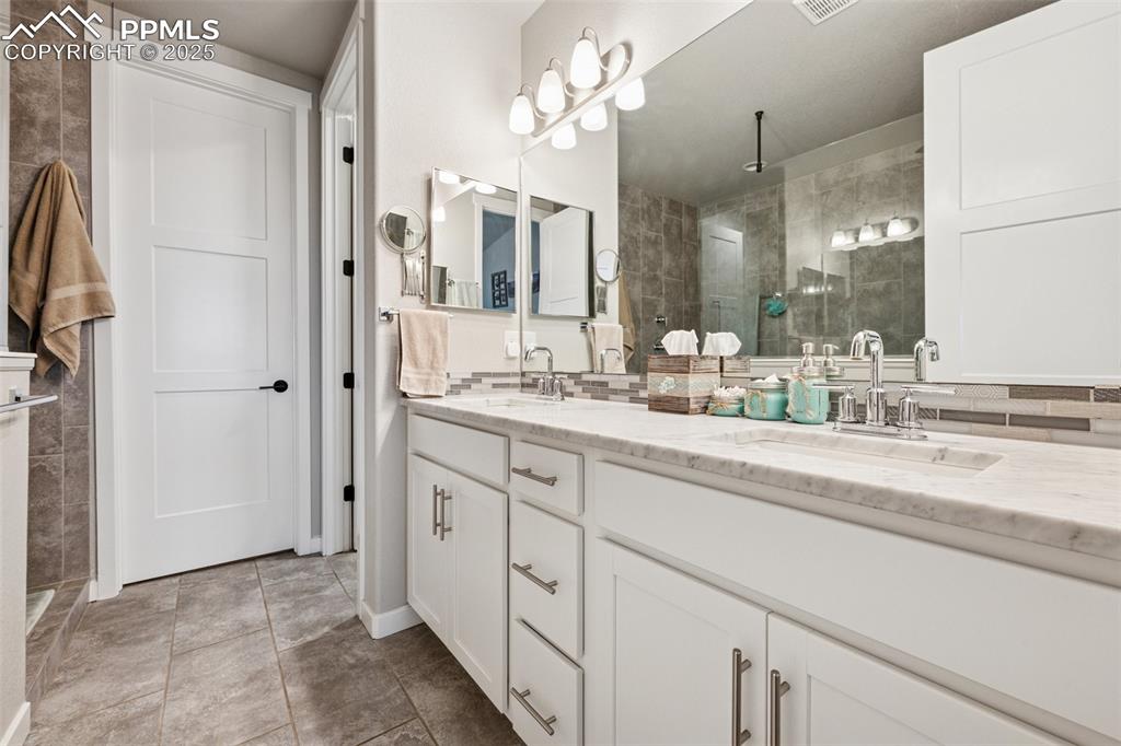 Image 19 of 40: Bathroom with walk in shower, double vanity, tile patterned flooring