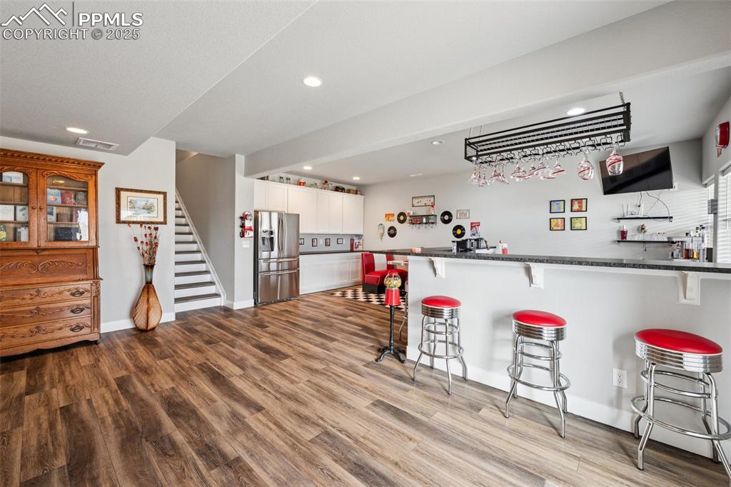 Image 34 of 40: Indoor bar featuring stainless steel refrigerator with ice dispenser, reces
