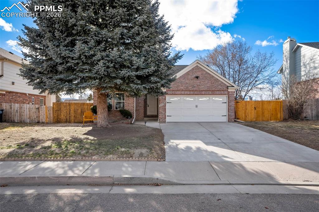 Image 1 of 43: View of property hidden behind natural elements with brick siding, a garage