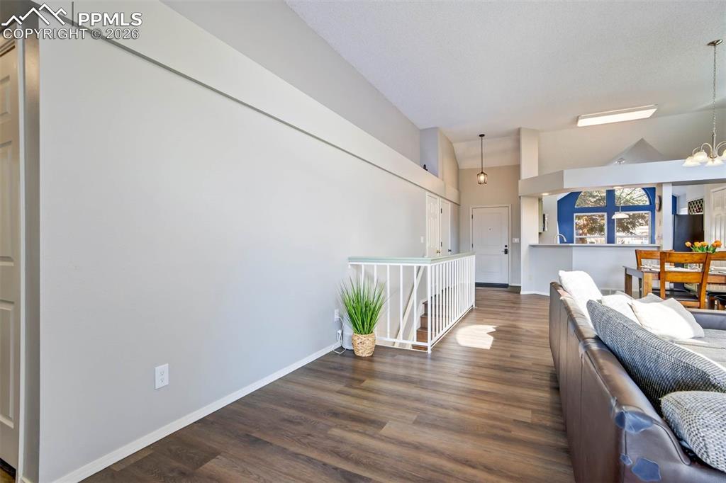 Image 10 of 43: Living area with dark wood-style floors and a chandelier