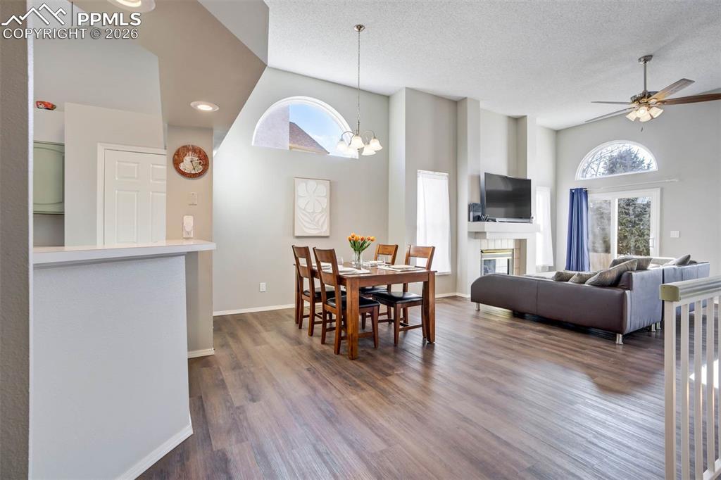 Image 13 of 43: Dining space with a ceiling fan, dark wood-type flooring, a tile fireplace,