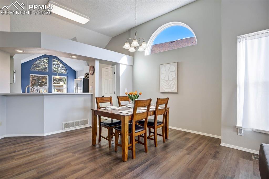 Image 14 of 43: Dining space with lofted ceiling, hanging lights, and dark wood-style floor