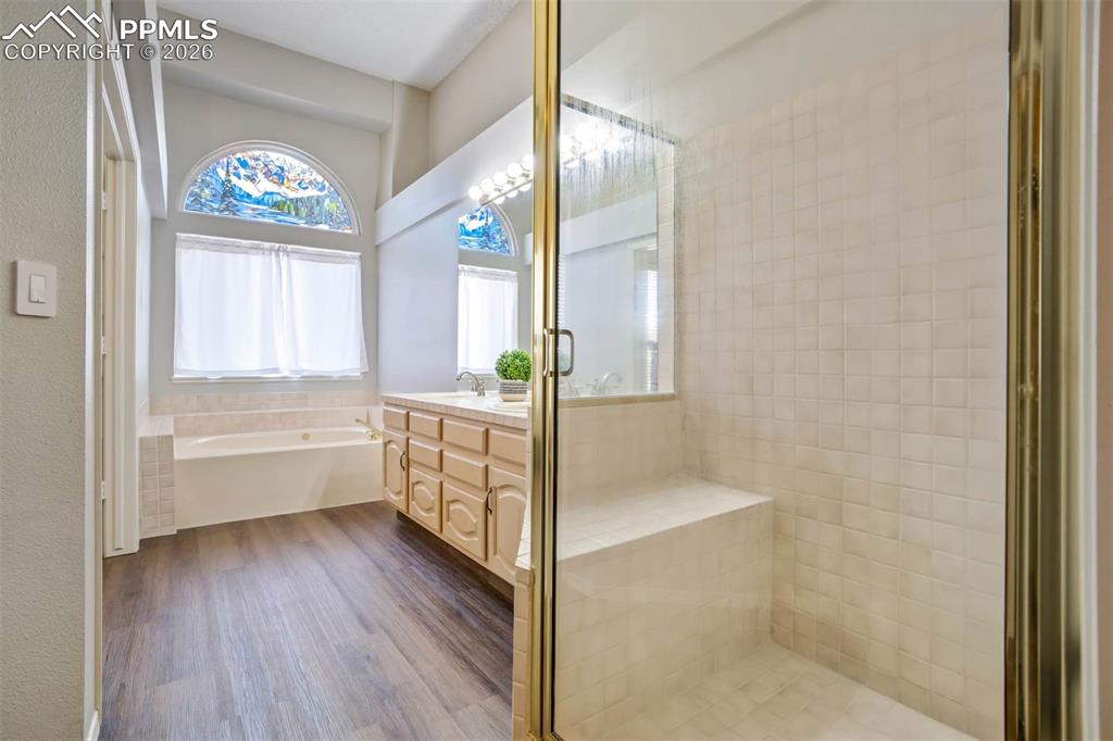 Image 22 of 43: Full bath featuring double vanity, a shower stall, and jet tub