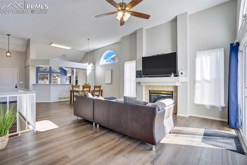 Image 6 of 43: Living area with vaulted ceiling, a ceiling fan, wood finished floors, a ti