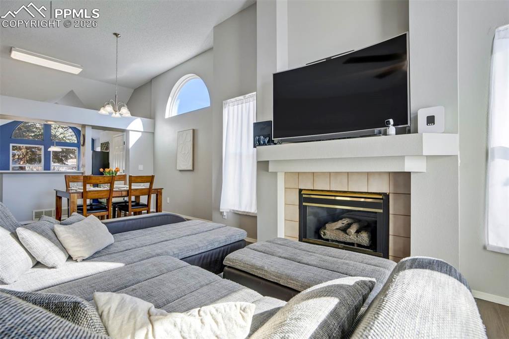 Image 7 of 43: Living room with lofted ceiling, suspended lighting, and a fireplace