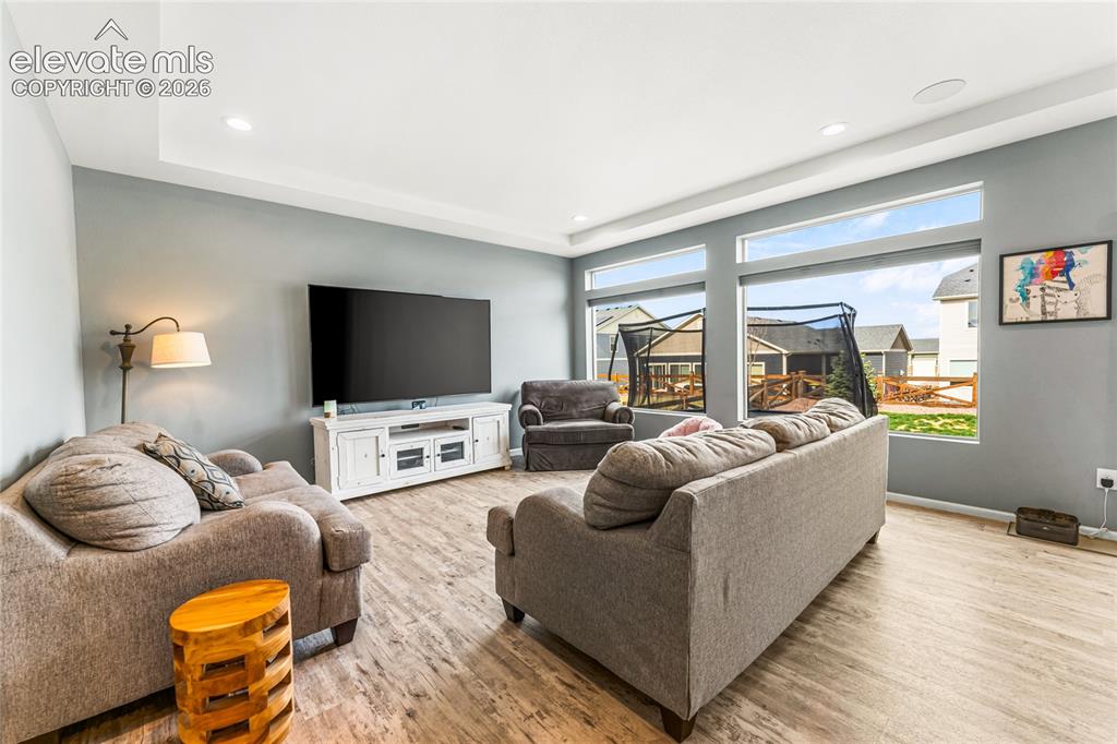 Image 13 of 32: Spacious room featuring tray ceiling, two ceiling fans, two large windows,