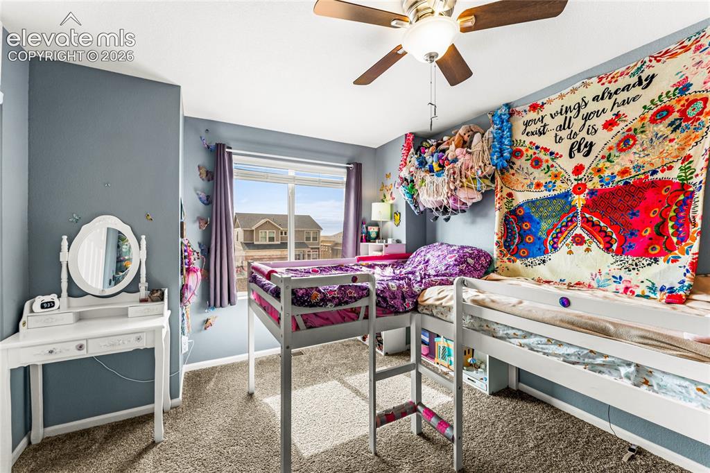 Image 22 of 32: Bedroom featuring a large window, textured carpeting, and a ceiling fan wit