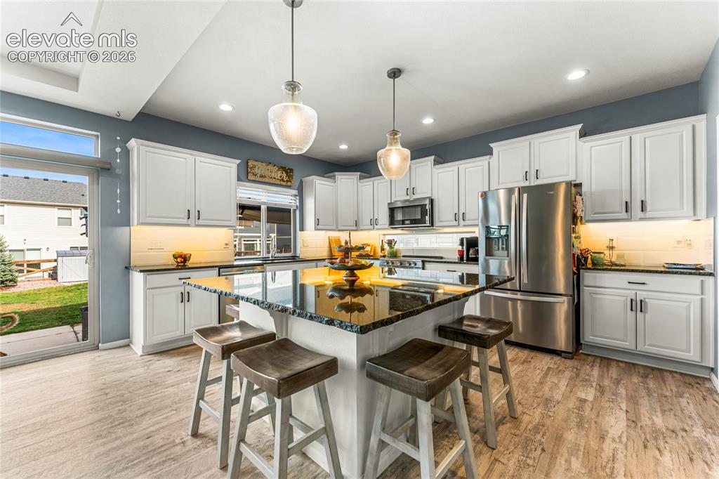 Image 7 of 32: Kitchen featuring white cabinetry, dark countertops, stainless steel applia