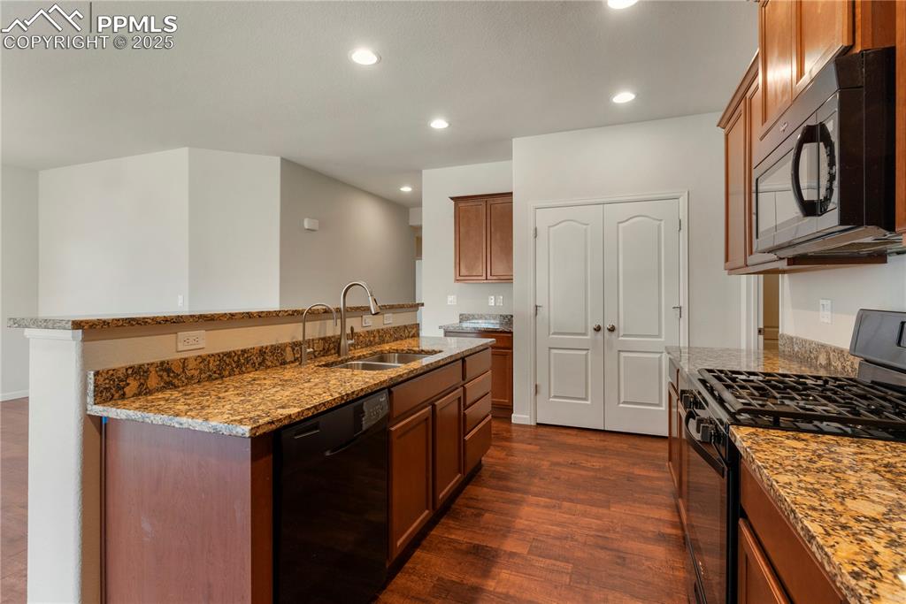Image 15 of 35: Kitchen featuring black appliances, granite countertops, open floor plan, d