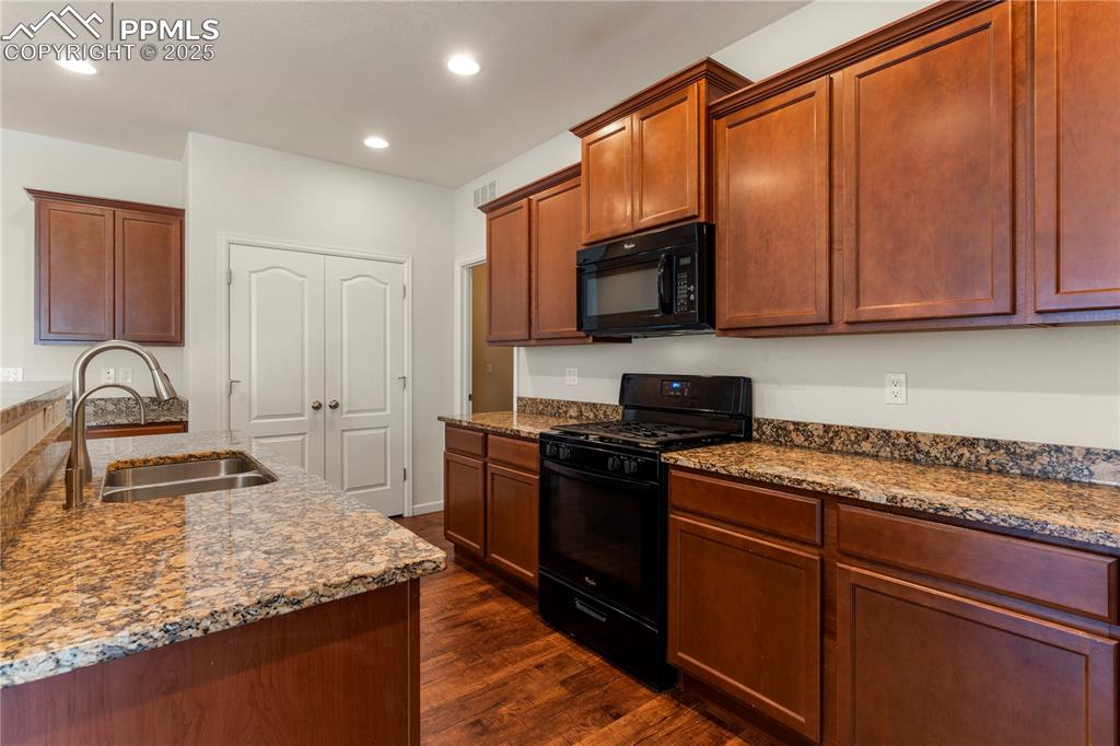 Image 16 of 35: Kitchen featuring black appliances, a sink, dark wood-type flooring, dark s