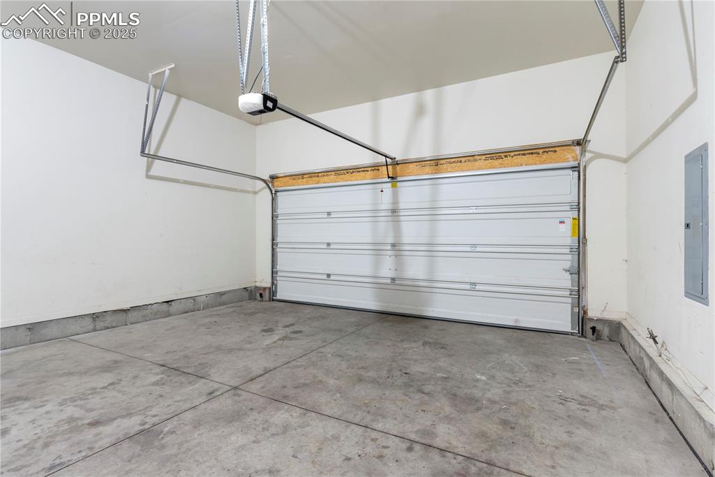 Image 18 of 35: Garage featuring a garage door opener and electric panel
