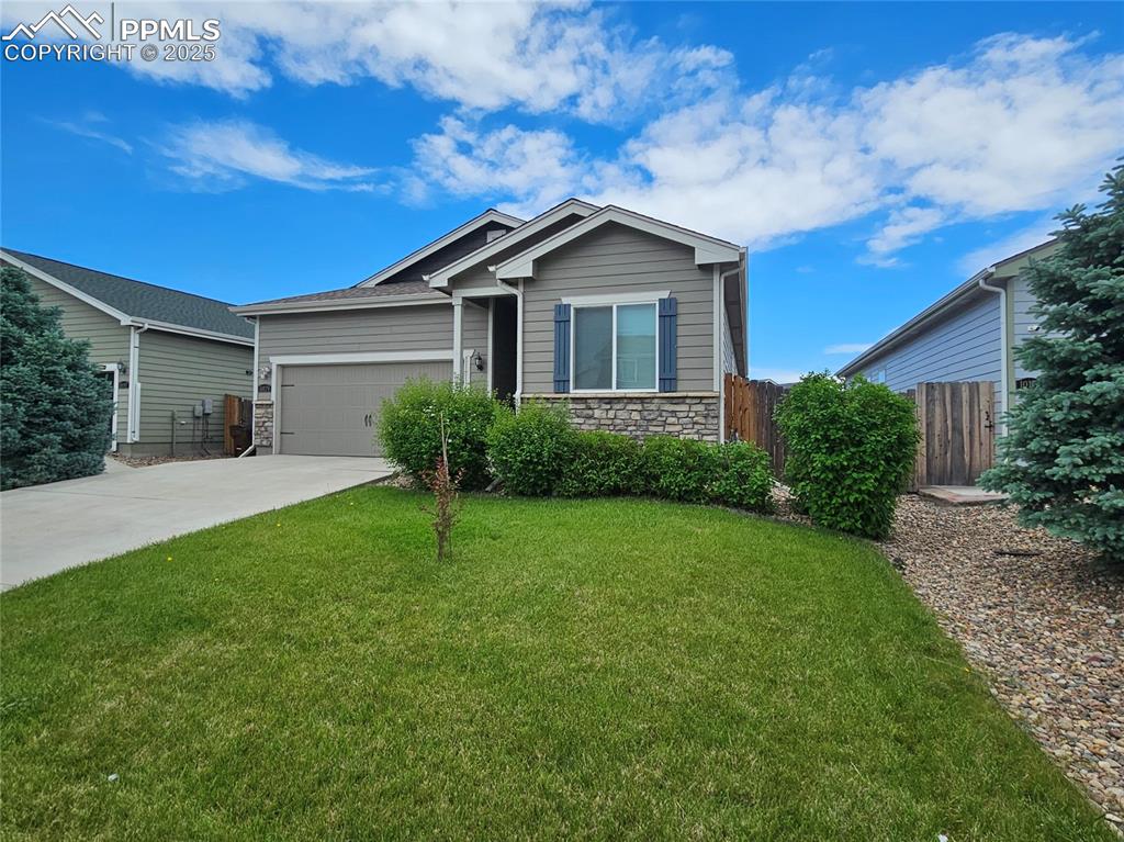 Image 2 of 35: Ranch-style house with stone siding, an attached garage, and driveway