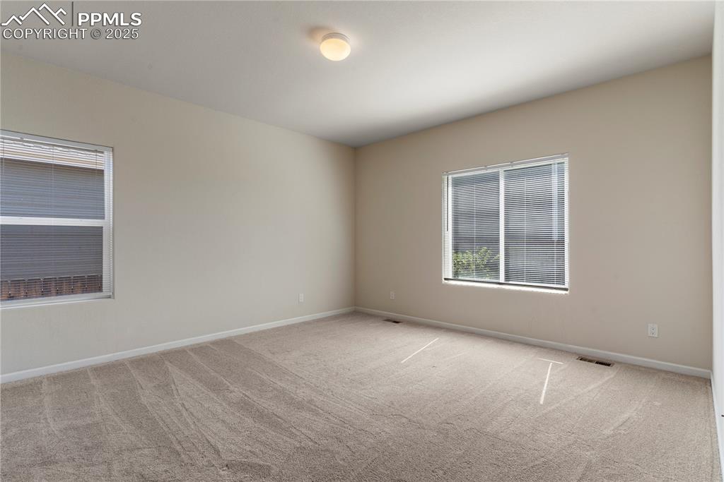 Image 22 of 35: Primary bedroom featuring light carpet, baseboards, ensuite bathroom, walk