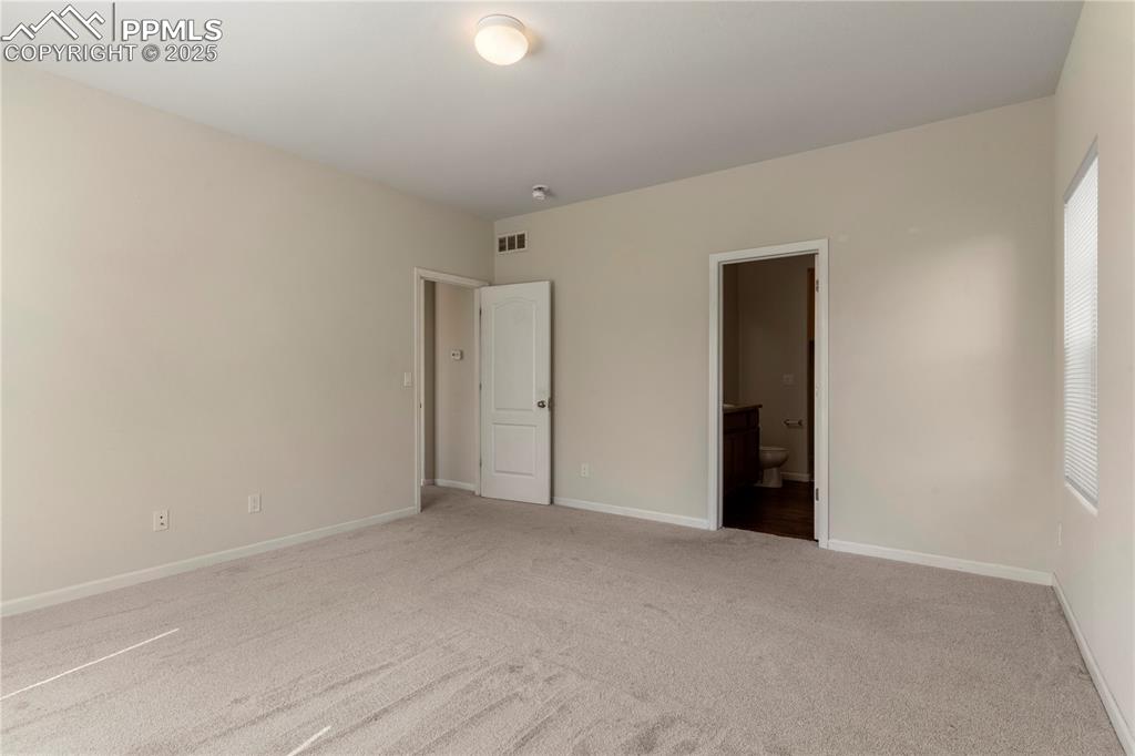 Image 23 of 35: Primary bedroom featuring light carpet, baseboards, ensuite bathroom, walk