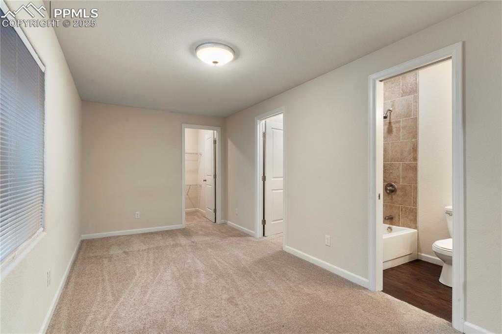 Image 28 of 35: Unfurnished bedroom with ensuite bathroom, carpet floors, and baseboards
