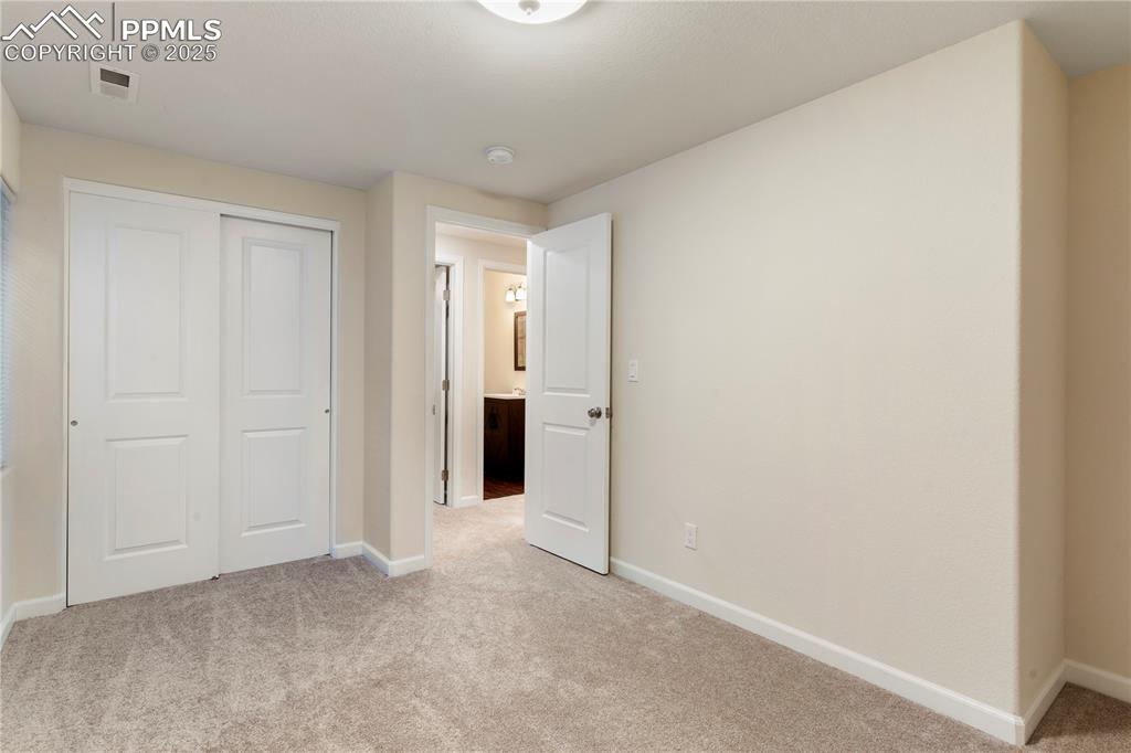 Image 30 of 35: Unfurnished bedroom with light carpet, baseboards, and a closet