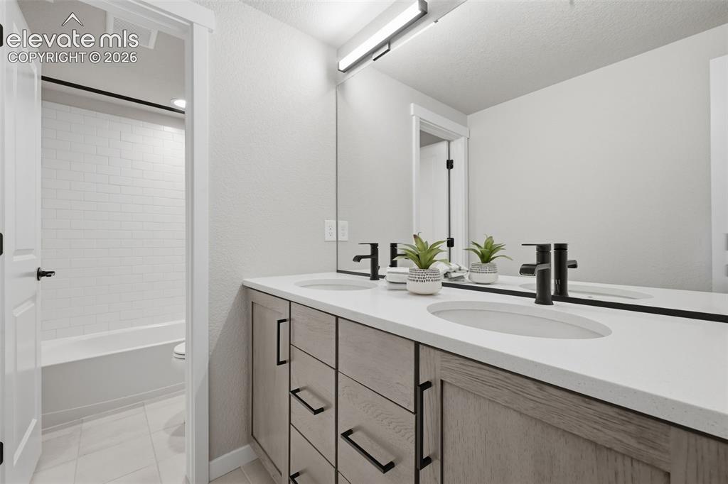 Image 26 of 33: Full bath in the basement with quartz counters and separate private area.