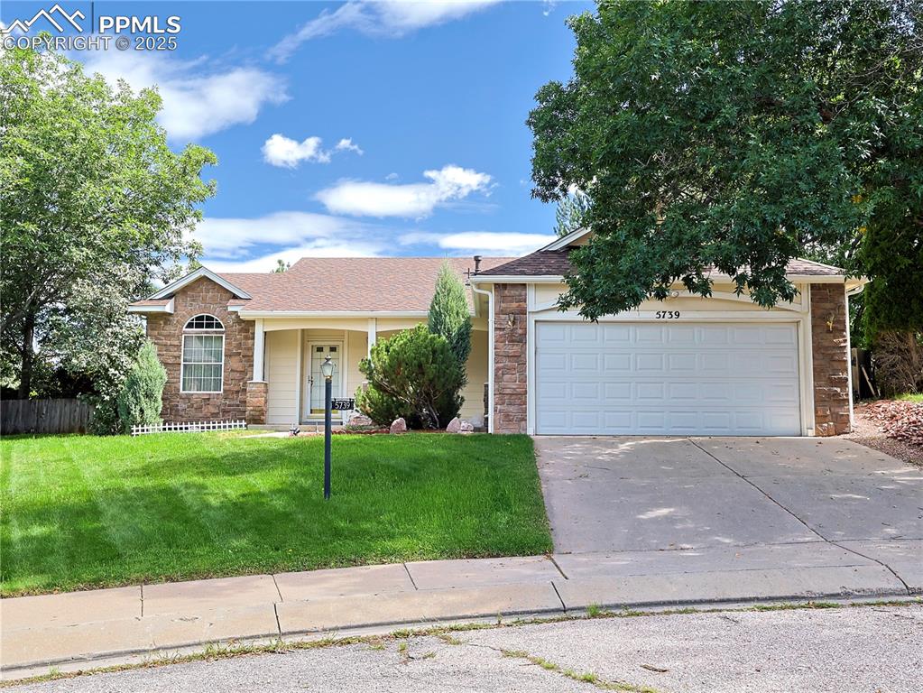 Caption: View of front of property with stone siding, covered porch, a garage, concrete driveway, and a shing
