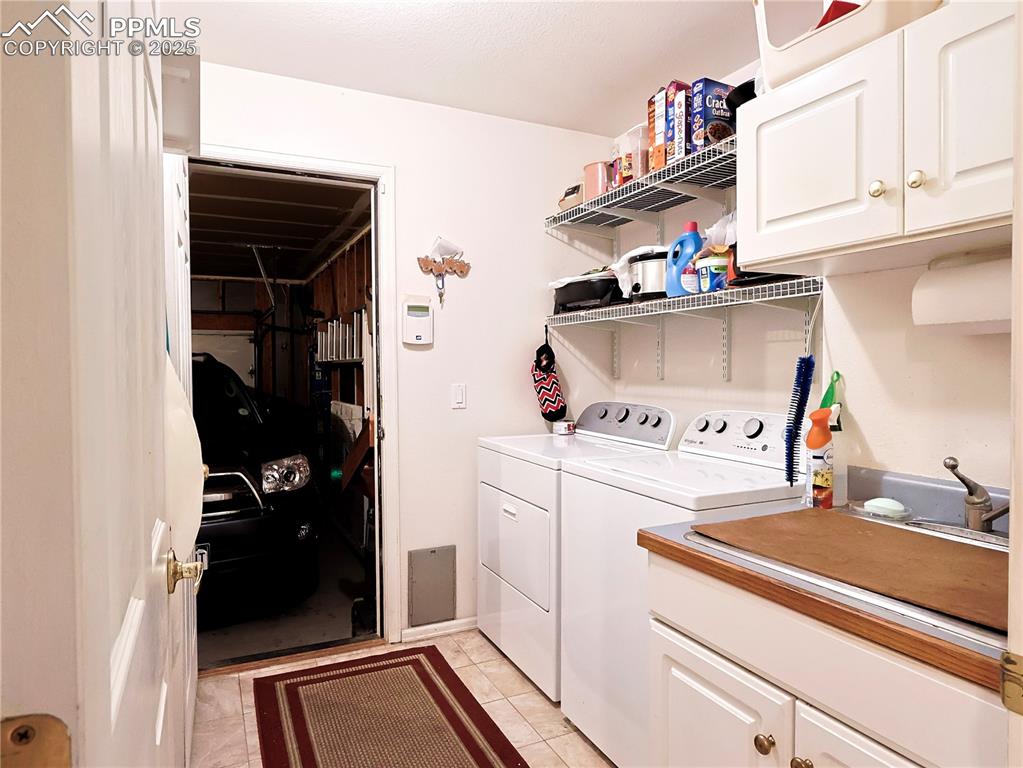 Image 15 of 29: Laundry room featuring cabinet space, light tile patterned floors, and wash