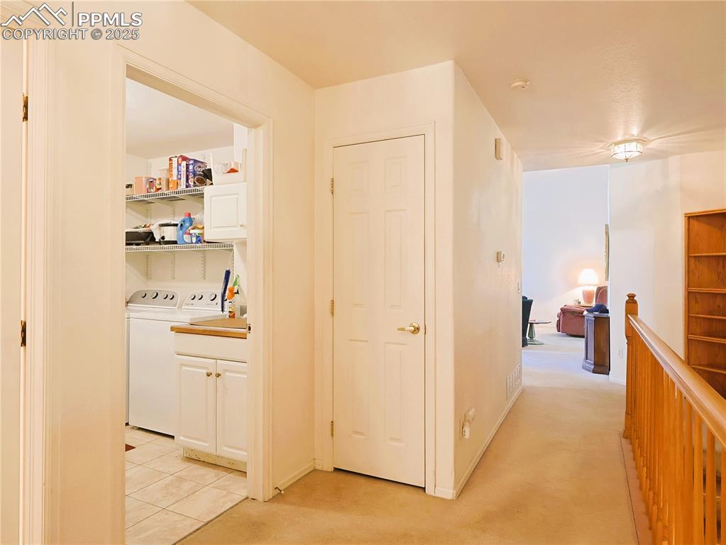 Image 16 of 29: Corridor with light colored carpet and washer and dryer