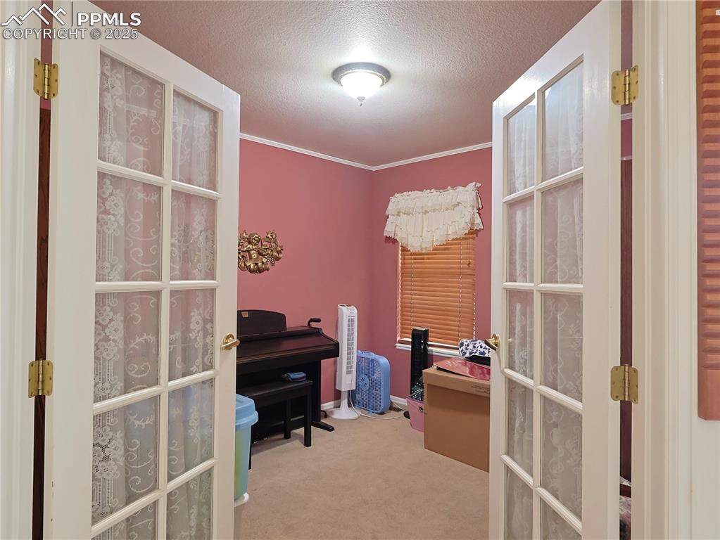Image 17 of 29: Office area featuring french doors, a textured ceiling, light carpet, and o