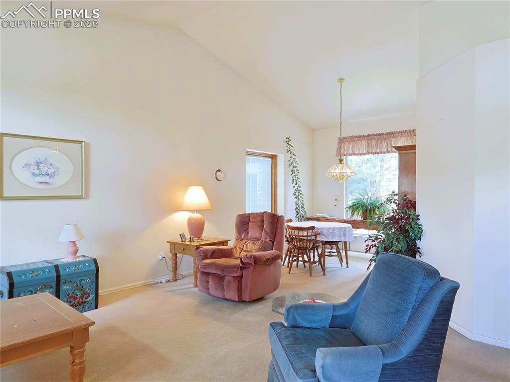 Image 2 of 29: Living room featuring carpet, high vaulted ceiling, and a chandelier