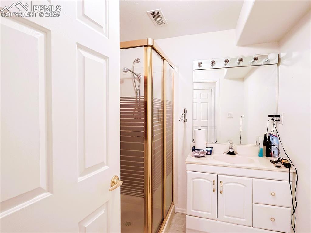 Image 20 of 29: Bathroom with a stall shower and vanity