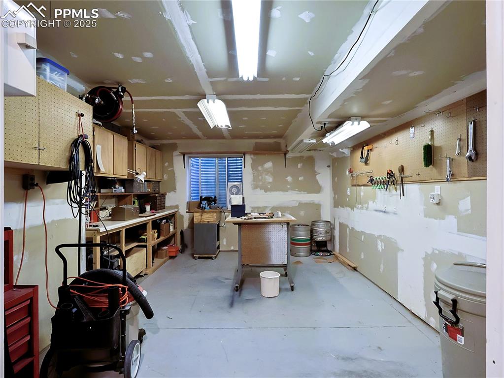 Image 24 of 29: Misc room featuring a workshop area and concrete flooring