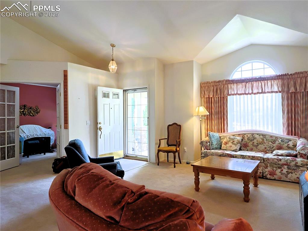 Image 3 of 29: Carpeted living room with vaulted ceiling and healthy amount of natural lig