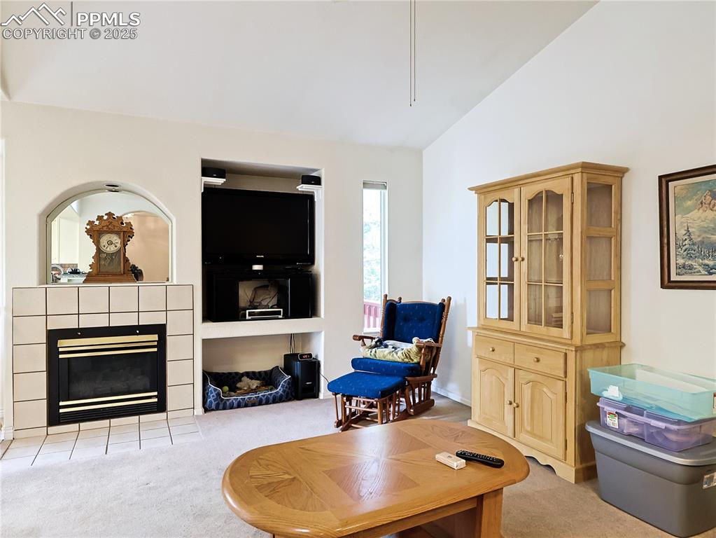 Image 5 of 29: Living room featuring light carpet, a fireplace, and vaulted ceiling