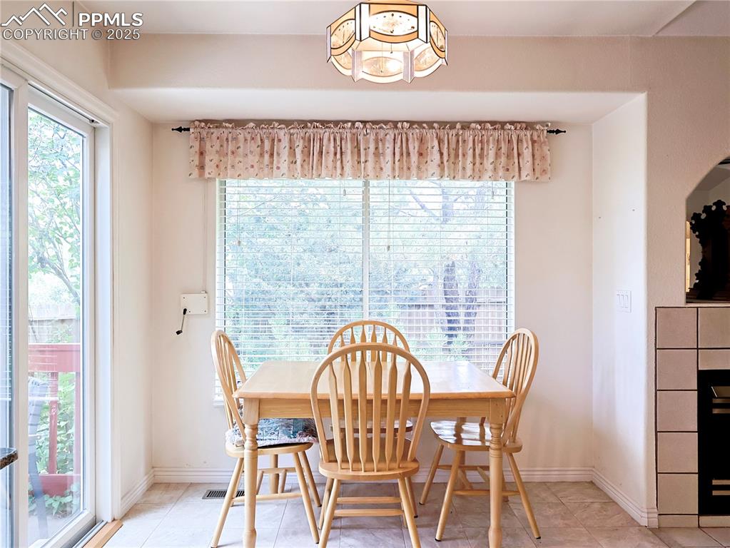 Image 6 of 29: Dining space featuring tile patterned flooring and a tile fireplace