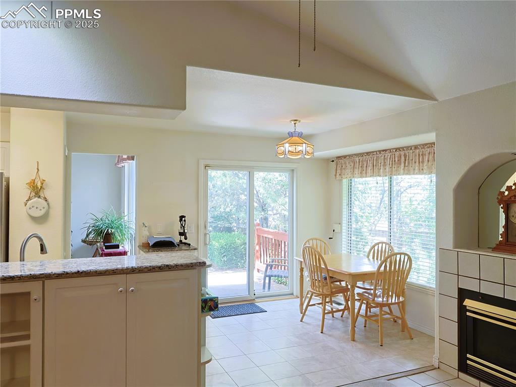 Image 9 of 29: Dining space with healthy amount of natural light, a tiled fireplace, and l