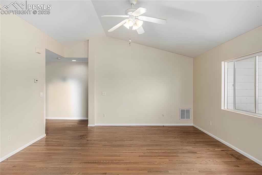 Image 7 of 26: The living room features ample natural lighting, hardwood flooring and vaul