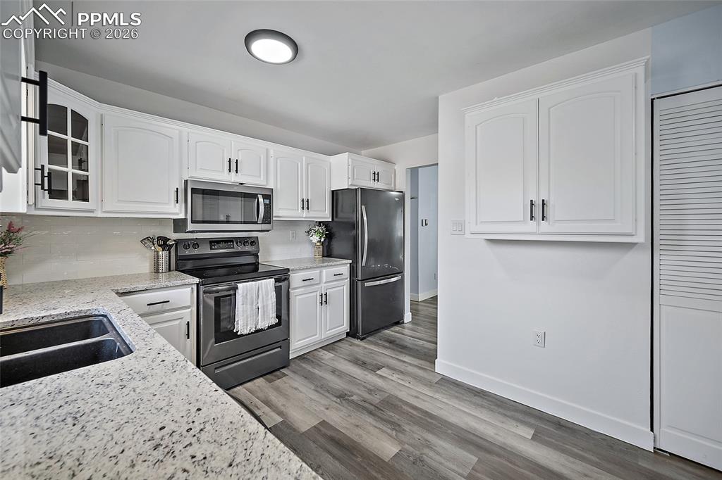 Image 9 of 38: Kitchen featuring stainless steel appliances with white cabinetry and grani