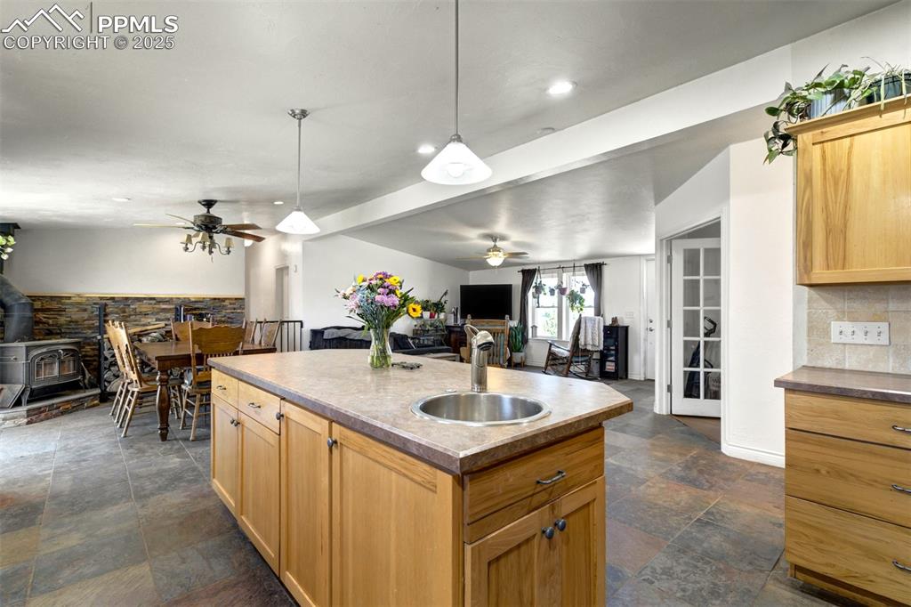 Image 10 of 50: Kitchen featuring a sink, stone finish floor, a ceiling fan, open floor pla