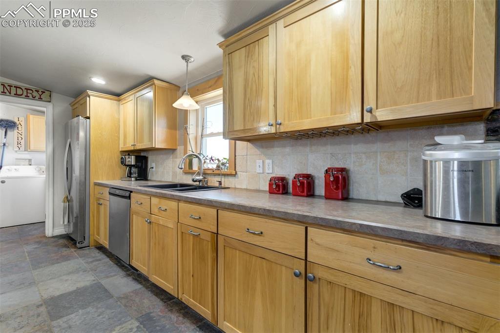 Image 15 of 50: Kitchen featuring washer / clothes dryer, stone finish floor, tasteful back