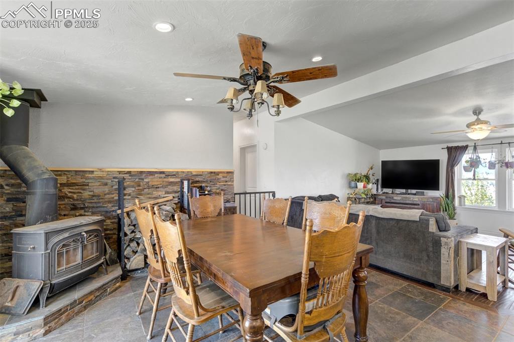 Image 16 of 50: Dining space featuring beamed ceiling, a wood stove, a ceiling fan, and rec
