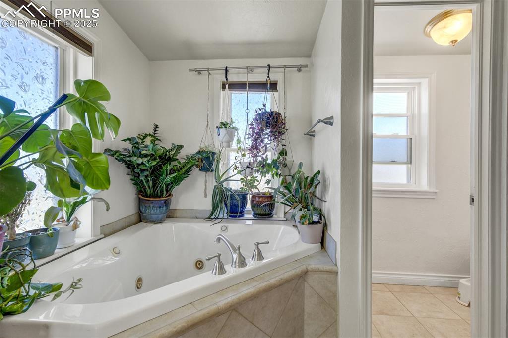 Image 27 of 50: Full bathroom with a whirlpool tub, baseboards, tile patterned floors, and 