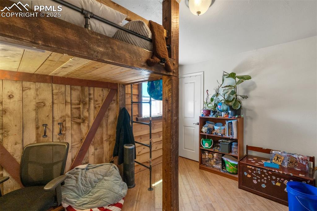 Image 28 of 50: Bedroom with wooden walls and wood finished floors