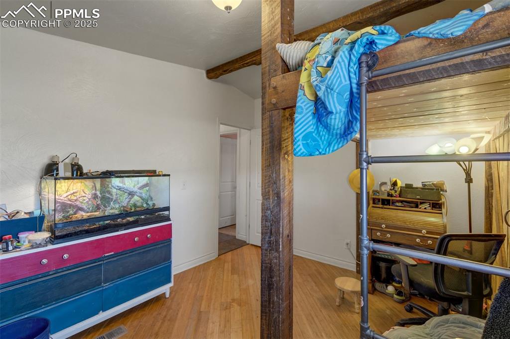 Image 29 of 50: Bedroom featuring baseboards, beamed ceiling, and wood finished floors