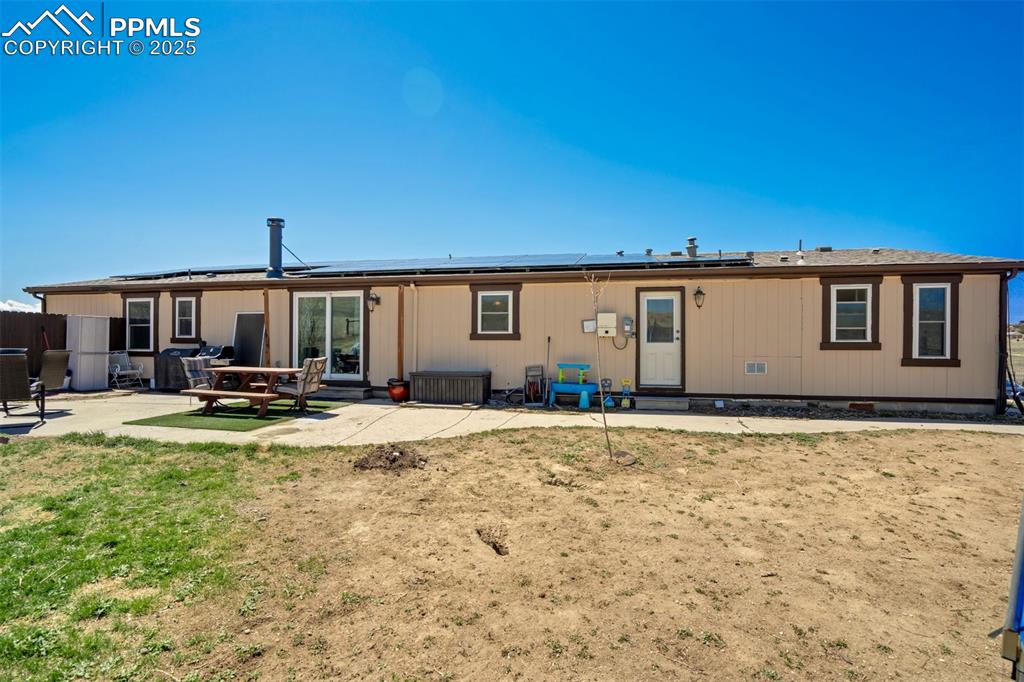 Image 36 of 50: Rear view of house featuring entry steps, fence, a patio, and solar panels