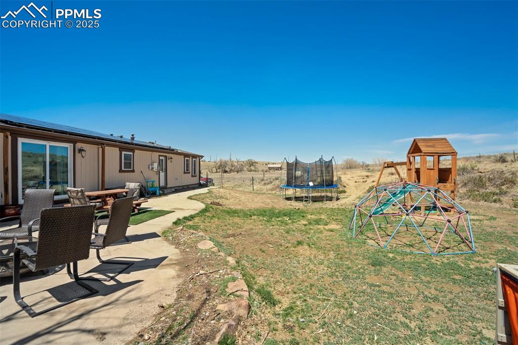Image 37 of 50: View of yard featuring a playground, a patio area, and a trampoline