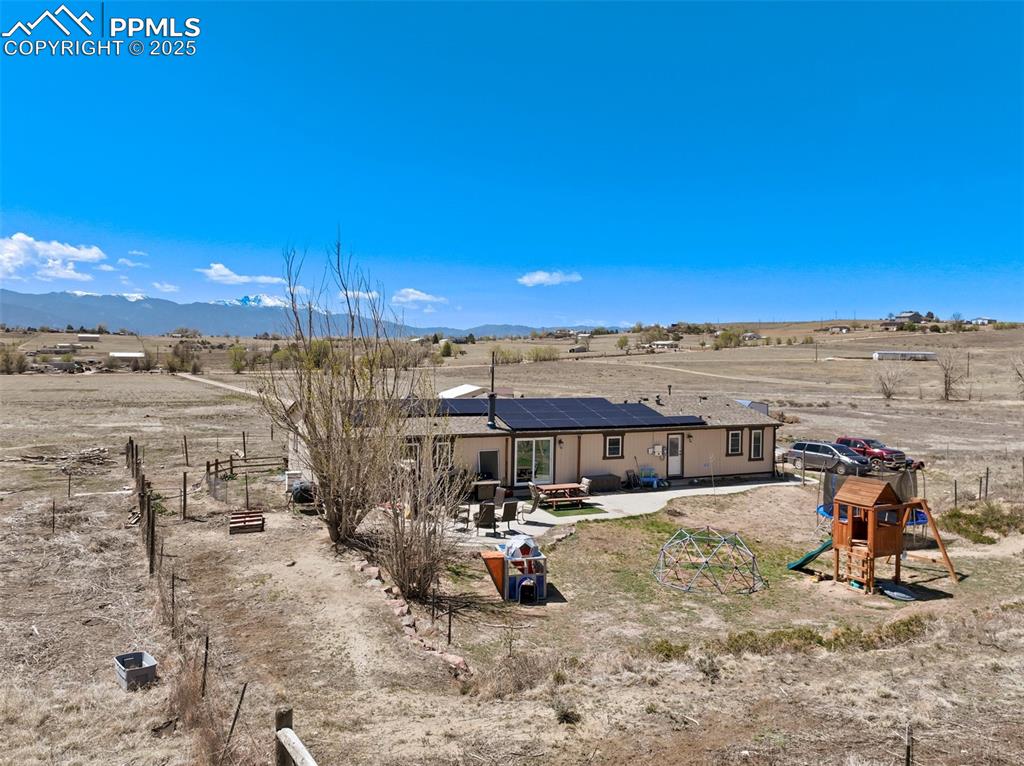 Image 46 of 50: Back of house featuring roof mounted solar panels, a playground, a patio ar