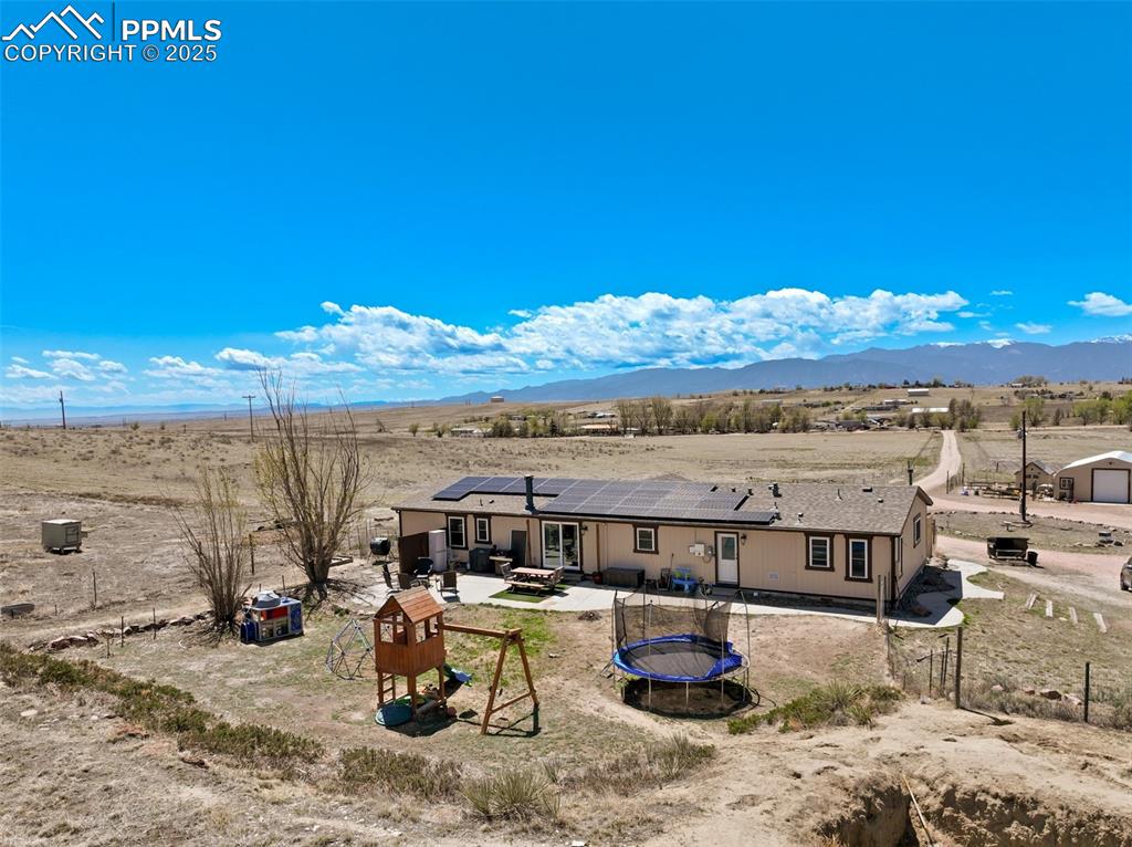 Image 47 of 50: Rear view of property featuring a trampoline, roof mounted solar panels, a 