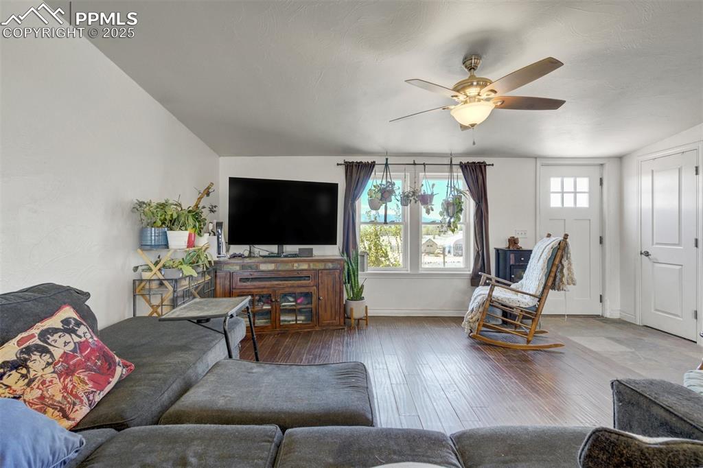 Image 6 of 50: Living area with baseboards, ceiling fan, and wood-type flooring