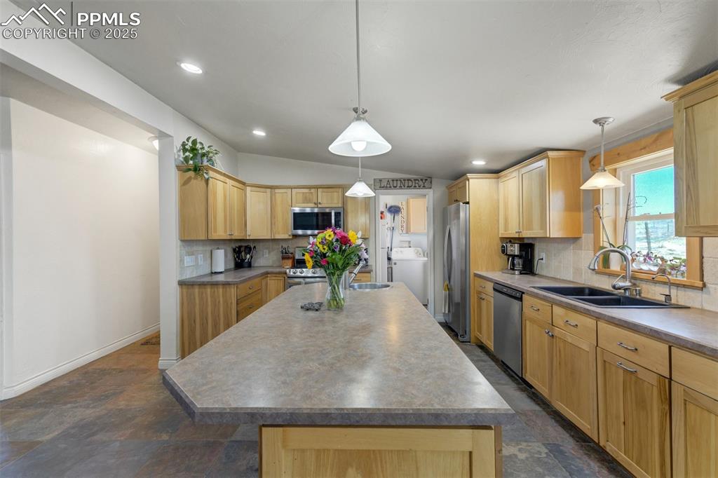 Image 8 of 50: Kitchen with light brown cabinetry, appliances with stainless steel finishe